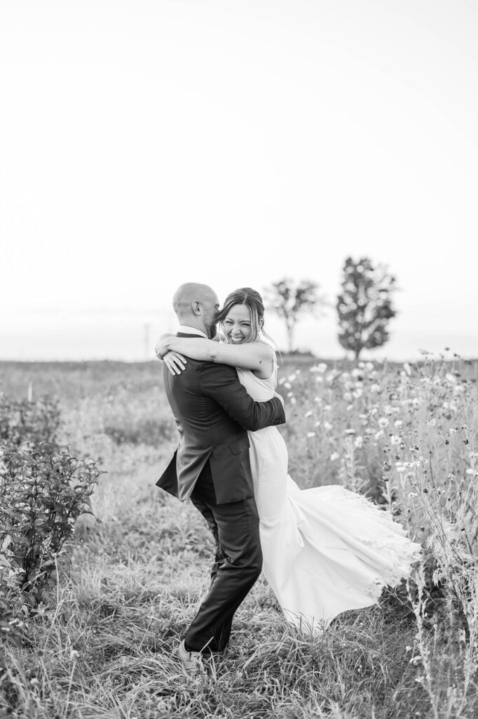 Bride and groom embracing in the cosmos flower field at Lavender Hill Farm after their wedding ceremony