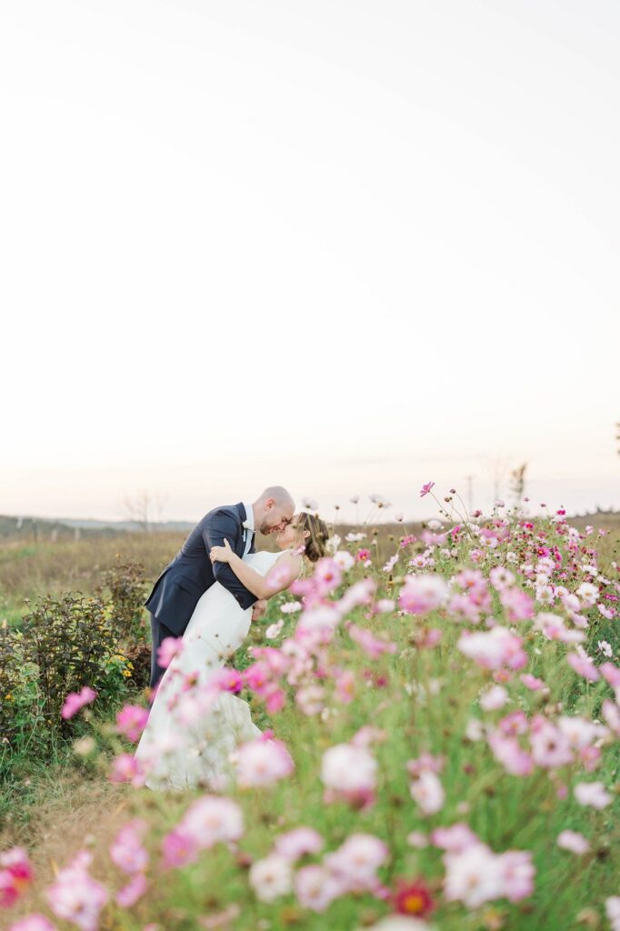Bride and groom embracing in the wildflowers during their Lavender Hill Farm wedding