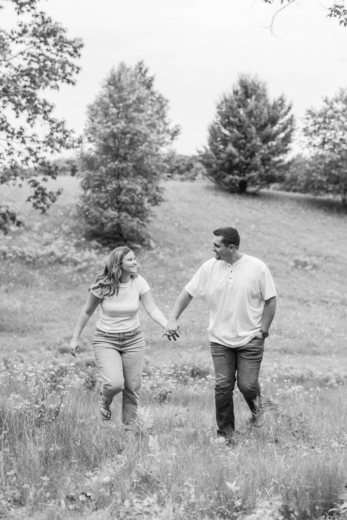 Madison and Jaxon walking hand in hand during their engagement session on the property where they plan to build their future home.