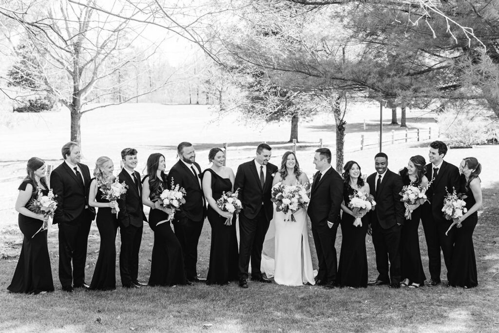 Full wedding party gathered for portraits at a Mill Pond Event Center wedding in Kalkaska, Michigan.