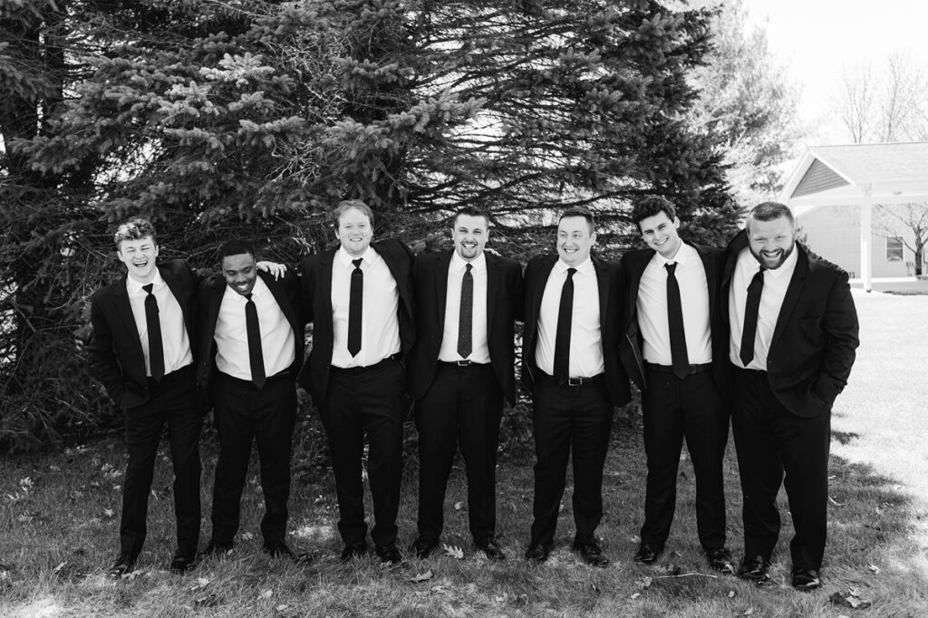 Groom and groomsmen sharing a laugh before a Northern Michigan wedding at Mill Pond Event Center.