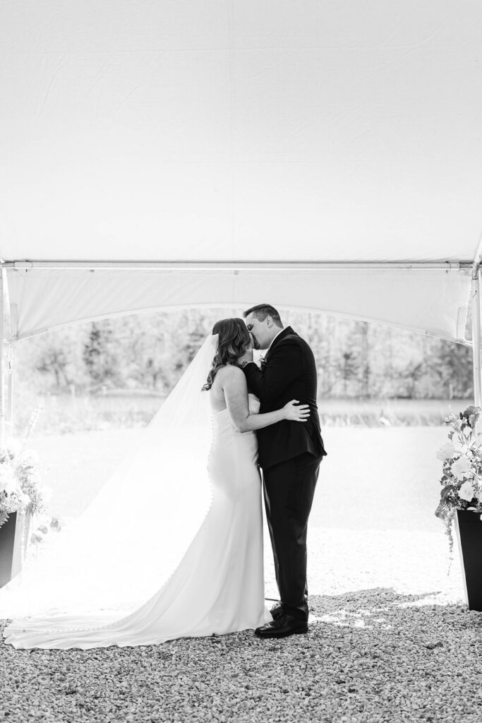 Madison and Jaxon sharing their first kiss during their Northern Michigan wedding ceremony at Mill Pond Event Center in Kalkaska, Michigan.