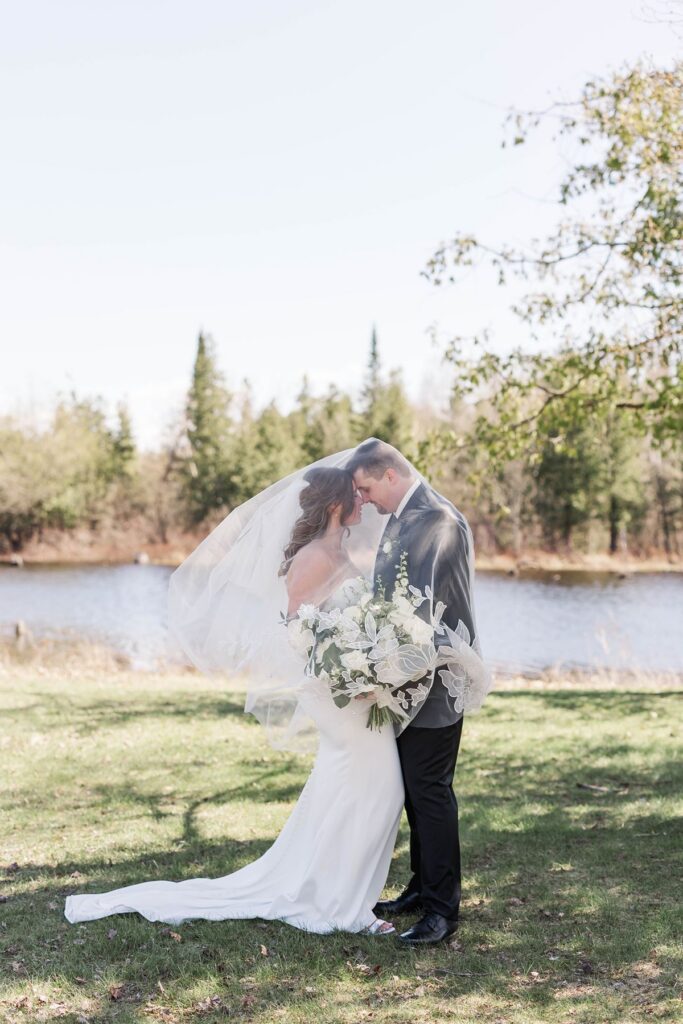 Madison and Jaxon sharing a quiet moment beneath her veil during their Northern Michigan wedding at Mill Pond Event Center.