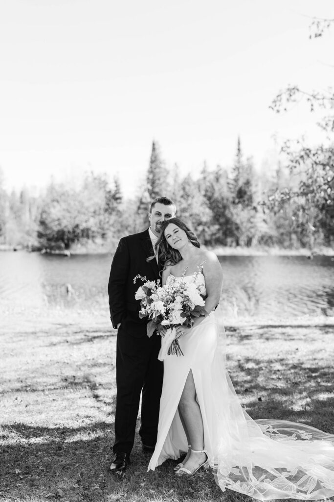 Madison and Jaxon embracing by the water during portraits at their Mill Pond Event Center wedding in Kalkaska, Michigan.