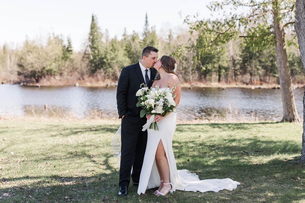 Bride and groom sharing a quiet moment by the water after their wedding ceremony at Mill Pond Event Center in Kalkaska, Michigan.