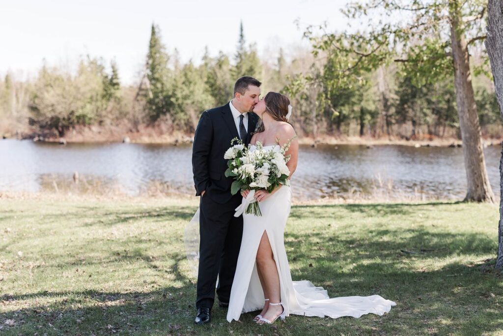 Bride and groom sharing a quiet moment by the water after their wedding ceremony at Mill Pond Event Center in Kalkaska, Michigan.