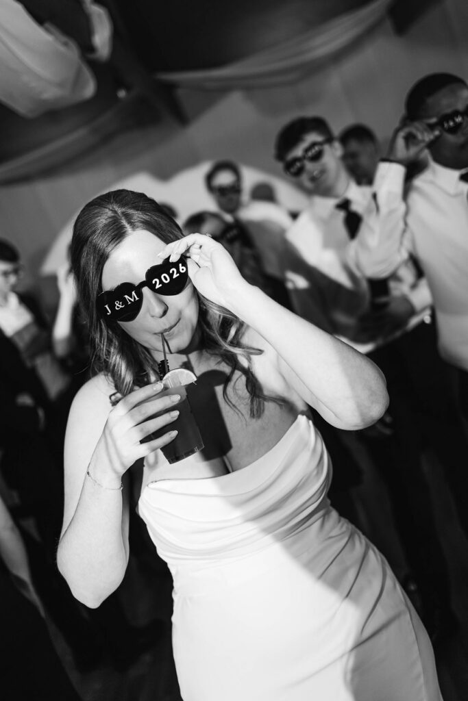 Madison celebrating on the dance floor in custom J&M 2026 party glasses during her Mill Pond Event Center wedding reception in Kalkaska, Michigan.