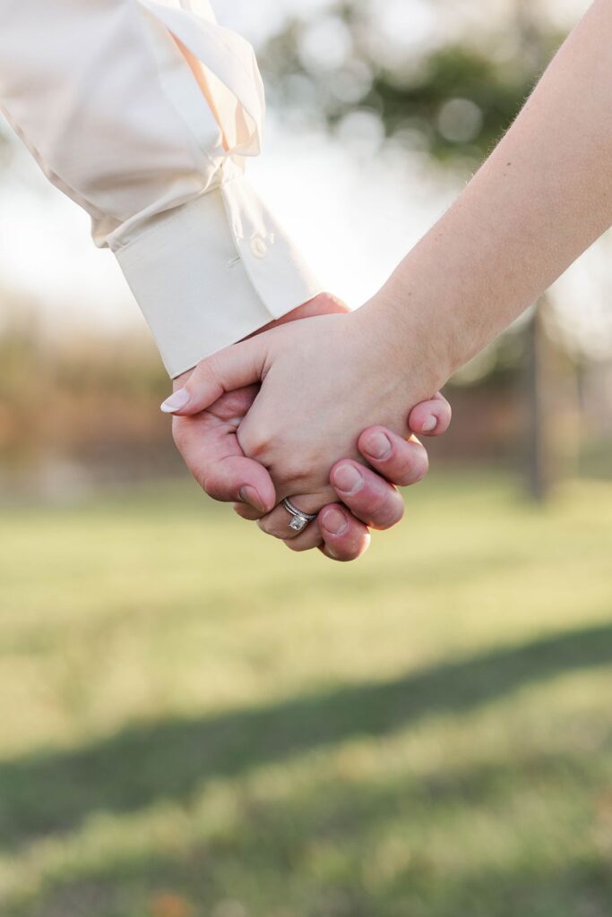 Close-up of Madison and Jaxon holding hands during lakeside wedding portraits at Mill Pond Event Center in Kalkaska, Michigan.