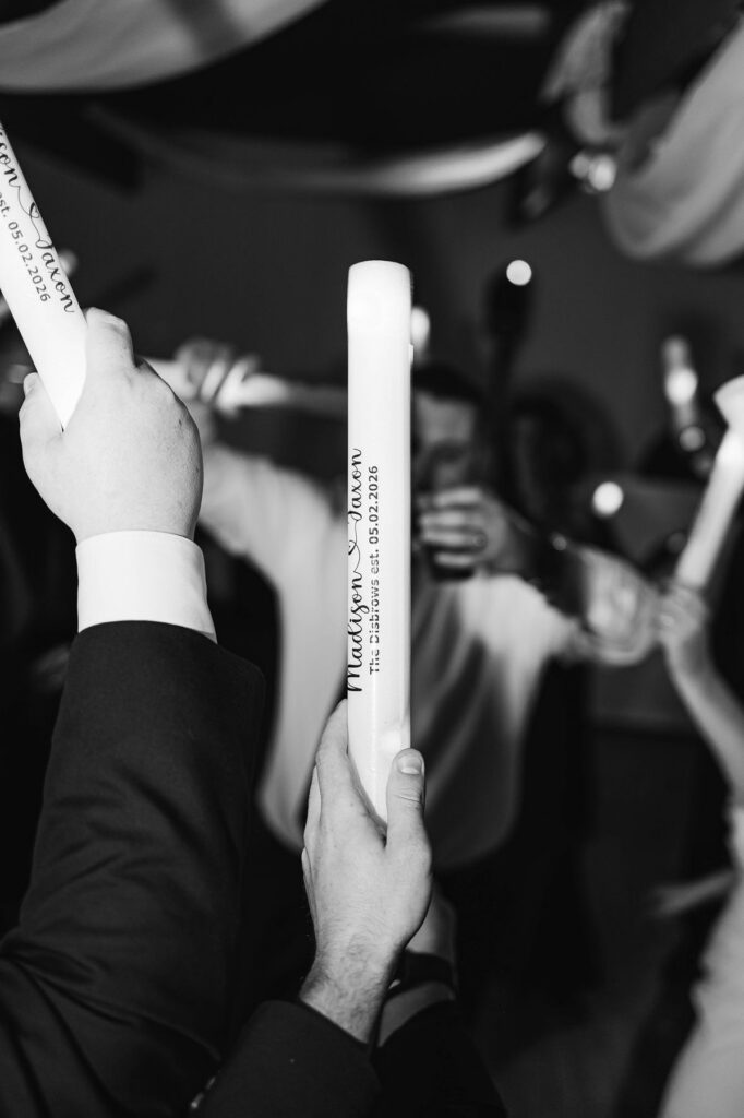 Candid black-and-white dance floor photo featuring custom wedding foam glow sticks during Madison and Jaxon's reception at Mill Pond Event Center.