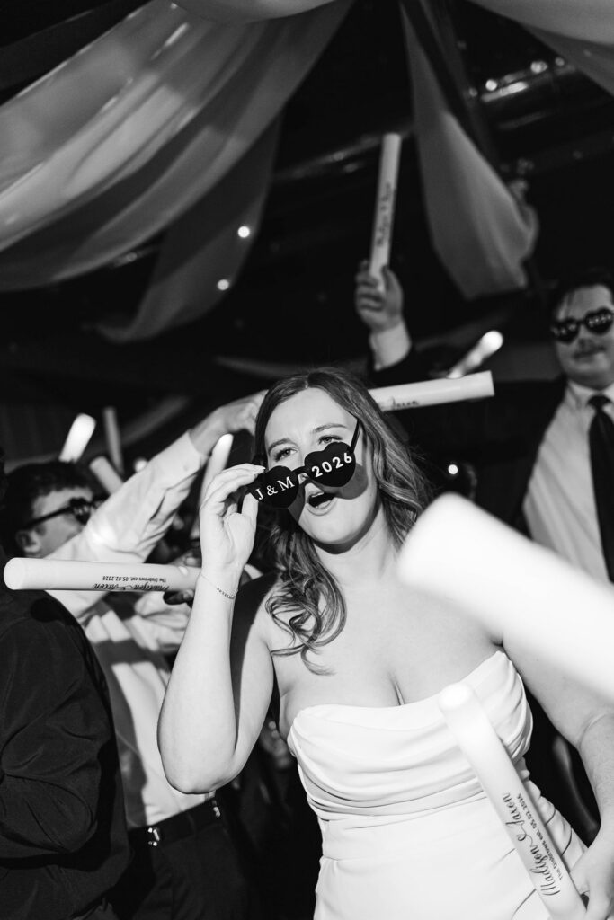 Bride dancing with custom wedding sunglasses as guests fill the dance floor during the reception at Mill Pond Event Center.