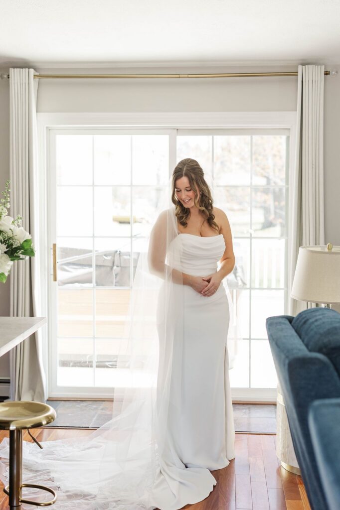 Bride standing by the window before her Northern Michigan wedding at Mill Pond Event Center in Kalkaska, Michigan.