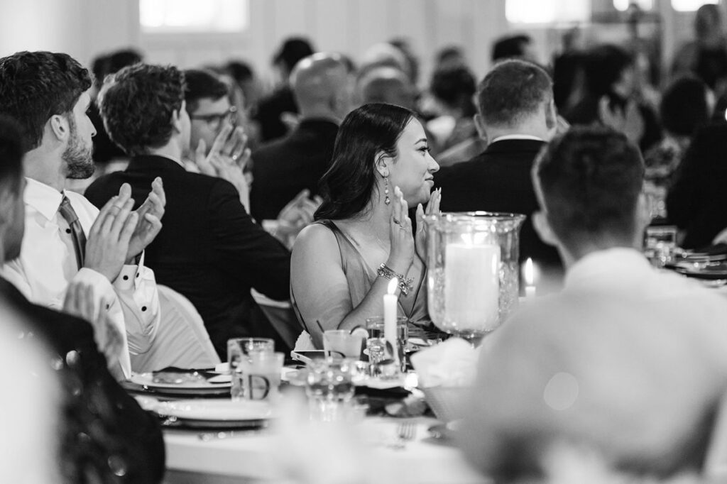 Wedding guests applauding during reception toasts at Madison and Jaxon's Mill Pond Event Center wedding in Kalkaska, Michigan.