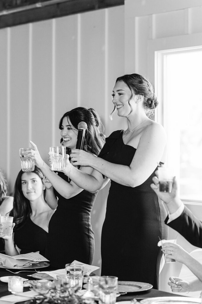 Bridesmaids raising a toast during heartfelt reception speeches at Madison and Jaxon's Mill Pond Event Center wedding in Kalkaska, Michigan.