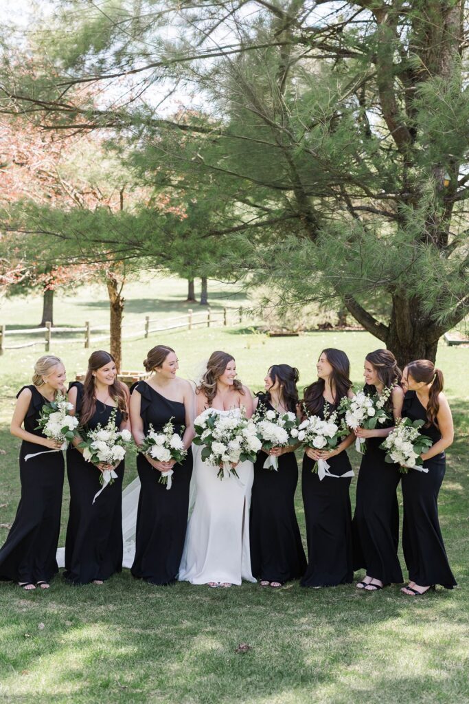 Bride and bridesmaids sharing a joyful moment during bridal party portraits at their Mill Pond Event Center wedding in Kalkaska, Michigan.