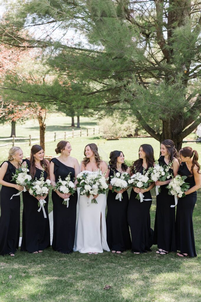 Bride and bridesmaids sharing a candid moment during wedding party portraits at Mill Pond Event Center.