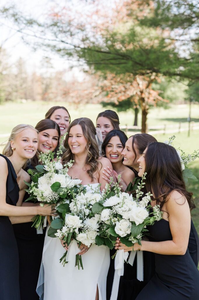 Bride surrounded by her bridesmaids during portraits at a Mill Pond Event Center wedding in Northern Michigan.
