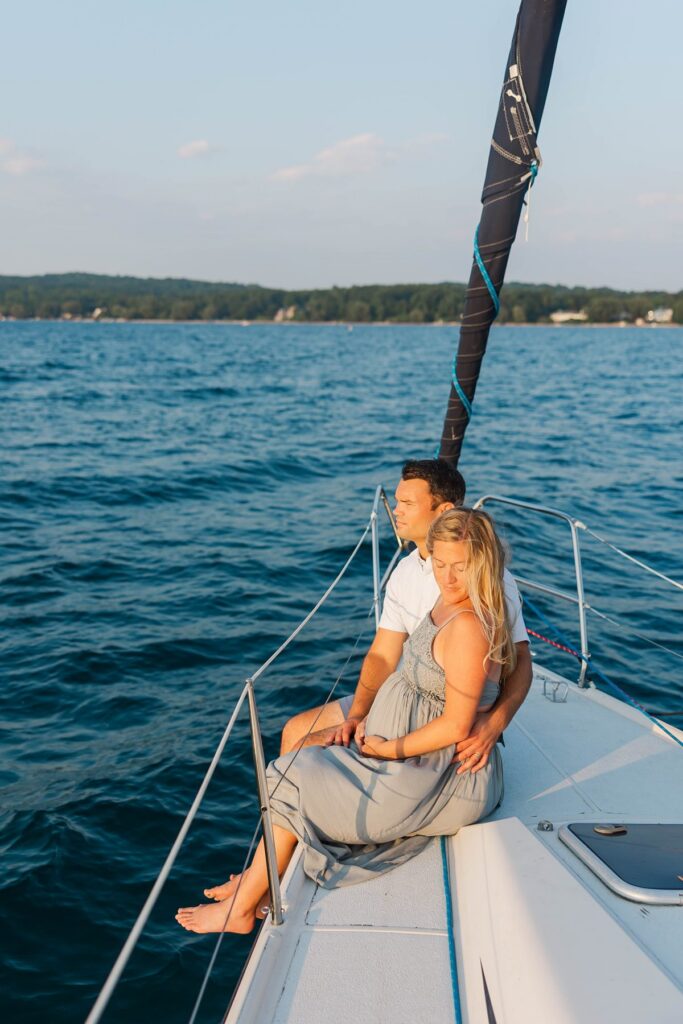 Couple relaxing aboard a sailboat during a sunset Traverse City sailboat photos session on Grand Traverse Bay