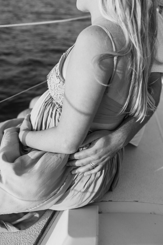 Close-up of a couple embracing during a sunset Traverse City sailboat photos session on Grand Traverse Bay