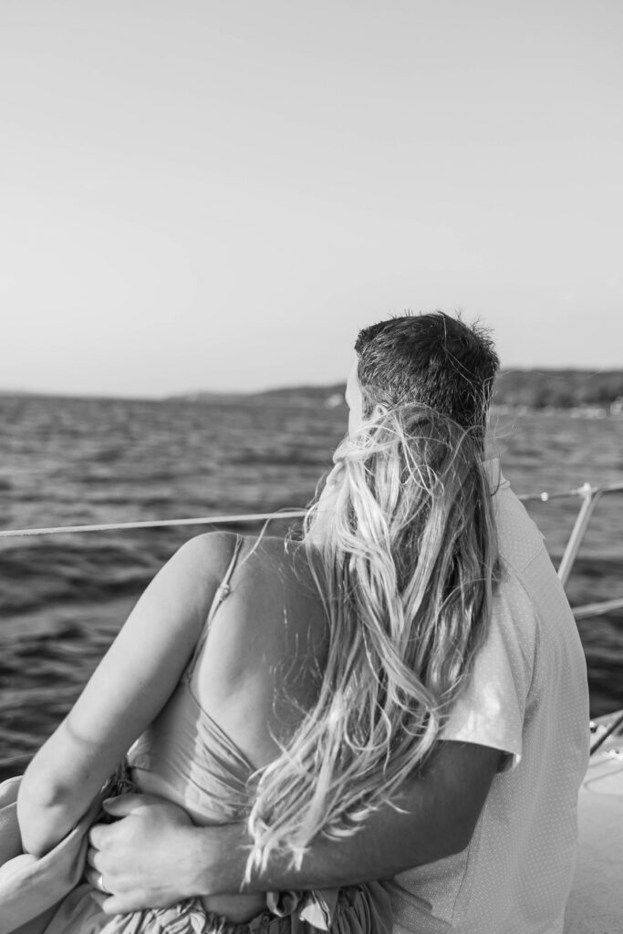 Couple watching the sunset aboard a sailboat during a Traverse City sailboat photos session on Grand Traverse Bay