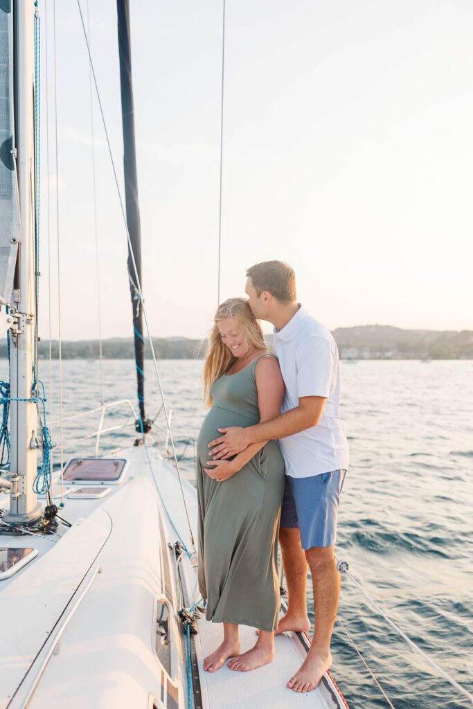 Couple embracing aboard a sailboat during a sunset Traverse City sailboat photos session on Grand Traverse Bay