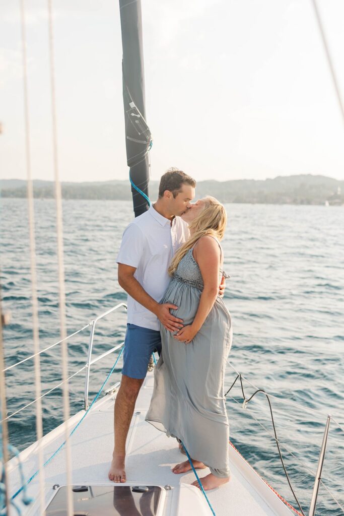 Couple embracing on a sailboat during a sunset Traverse City sailboat photos session on Grand Traverse Bay