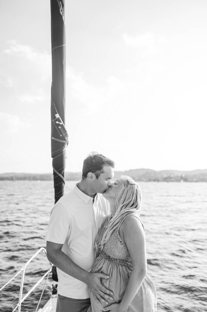 Couple kissing aboard a sailboat during a sunset Traverse City sailboat photos session on Grand Traverse Bay