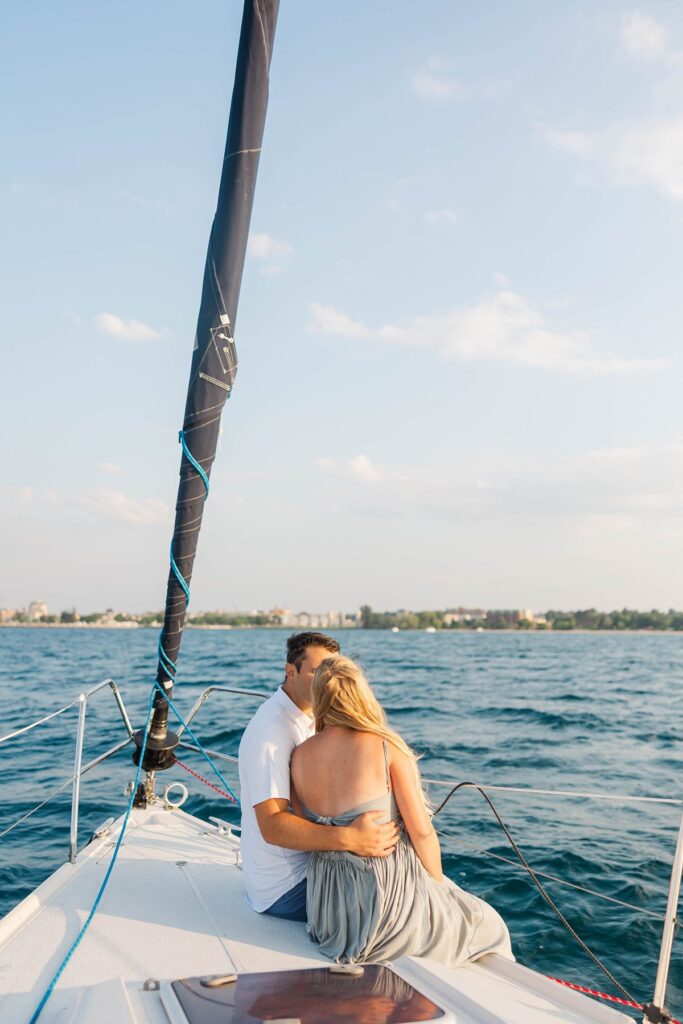 Couple sitting together on the bow during a sunset Traverse City sailboat photos session on Grand Traverse Bay