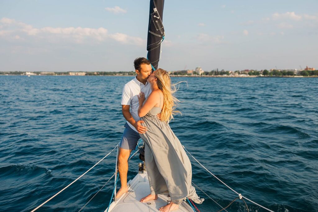 Couple kissing on the bow during a sunset Traverse City sailboat photos session on Grand Traverse Bay