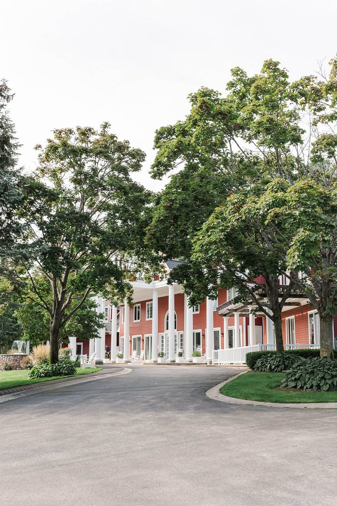 Exterior of the red Black Star Farms Inn with white columns and landscaped grounds in Suttons Bay, Northern Michigan.