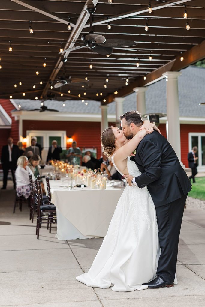 Allison and Cole share their first dance beneath warm string lights during their intimate wedding reception at Black Star Farms in Suttons Bay, Michigan.