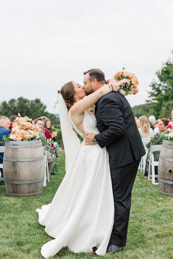 Allison and Cole sharing a kiss during their vineyard wedding ceremony at Black Star Farms in Suttons Bay, Northern Michigan.