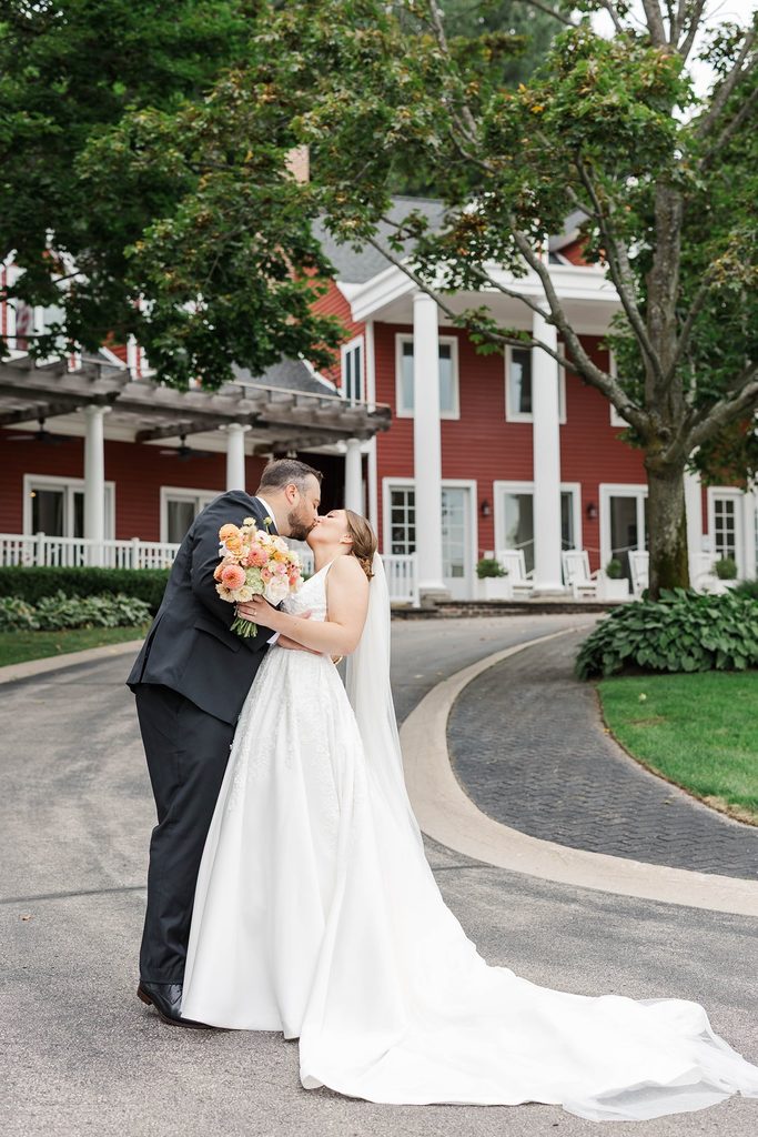 Allison and Cole embracing and kissing outside the Black Star Farms Inn during their intimate wedding in Suttons Bay, Northern Michigan.