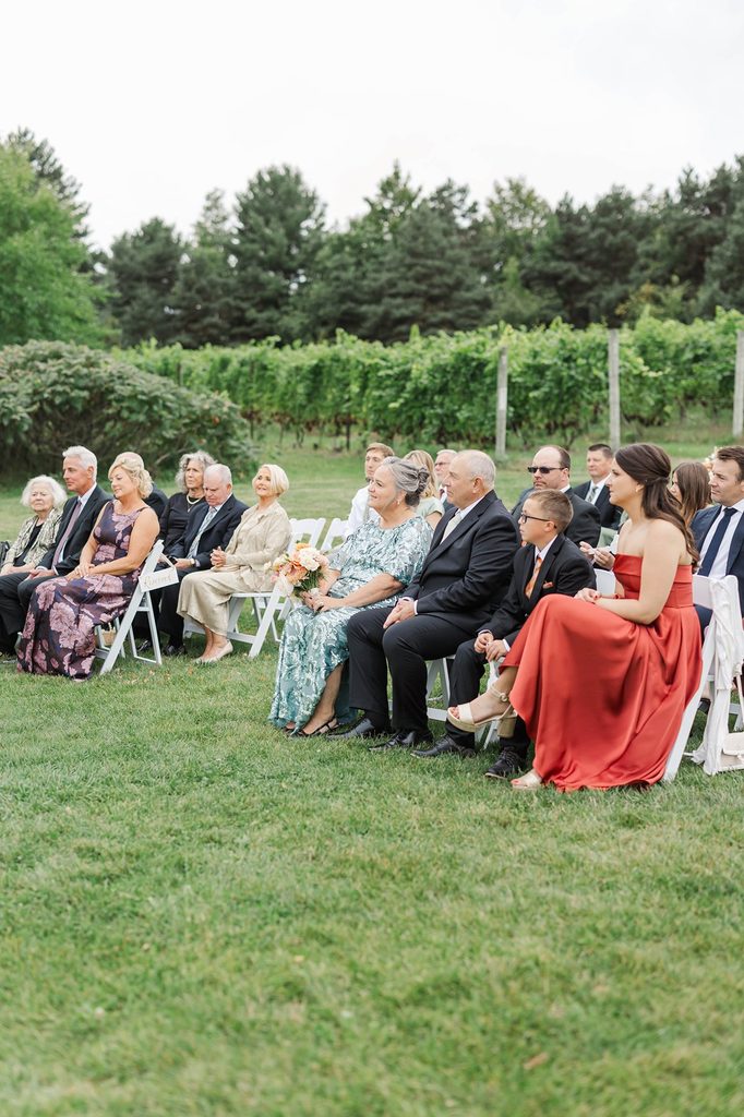 Wedding guests watching Allison and Cole's intimate outdoor ceremony overlooking the vineyards at Black Star Farms in Suttons Bay.