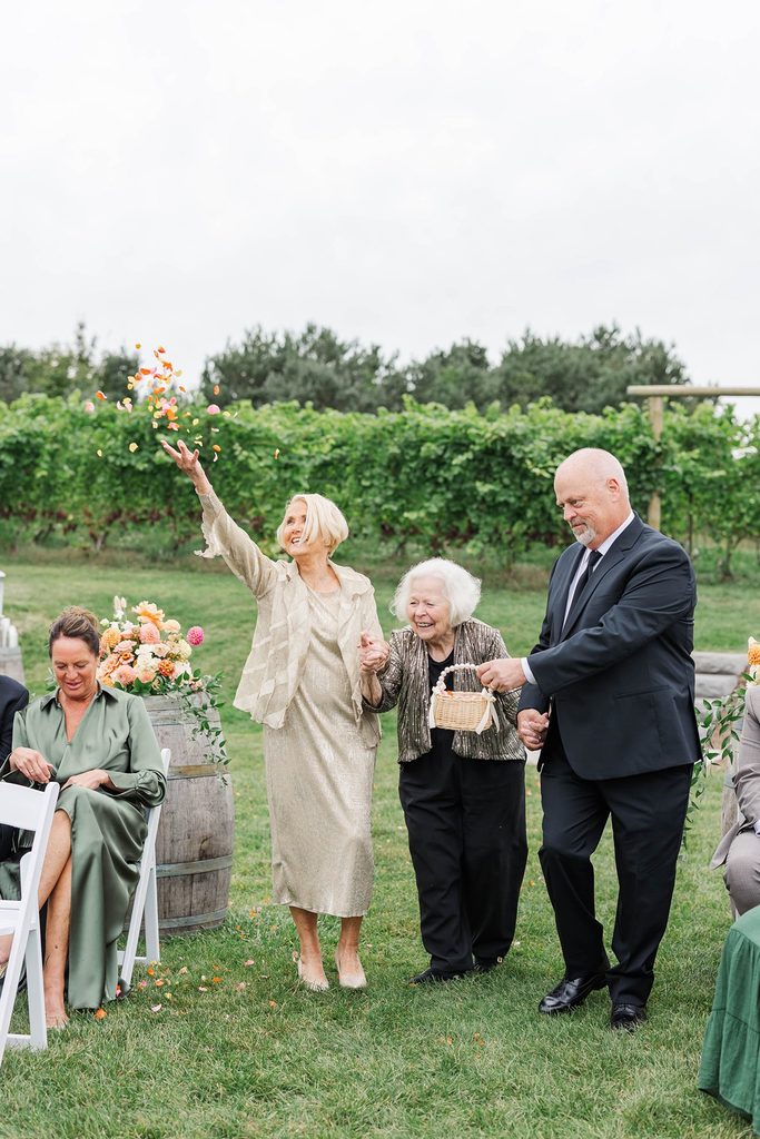 Allison's grandmother serving as the flower girl, tossing flower petals down the aisle during the couple's intimate Black Star Farms wedding ceremony.