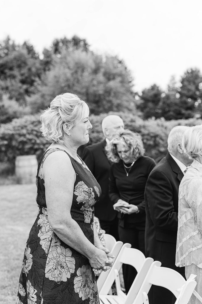 Black-and-white photograph of Allison's mother becoming emotional while watching the wedding processional at Black Star Farms in Suttons Bay, Michigan.