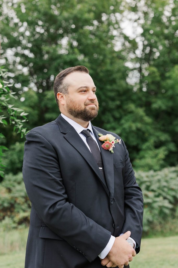 Cole standing at the outdoor vineyard ceremony site, waiting for Allison to walk down the aisle during their Black Star Farms wedding in Suttons Bay.
