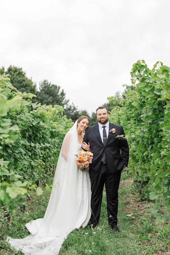 Allison and Cole posing together among the grapevines at Black Star Farms winery in Suttons Bay, Michigan.