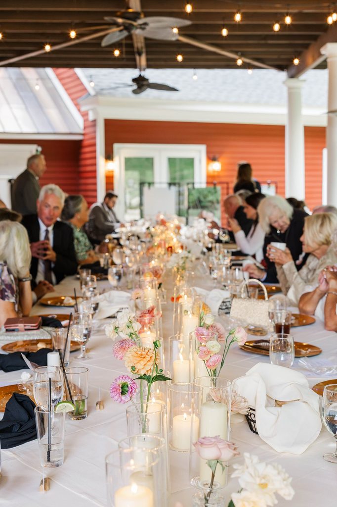 Wedding guests enjoying an intimate dinner around a long table decorated with colorful florals and candles at Black Star Farms in Northern Michigan.