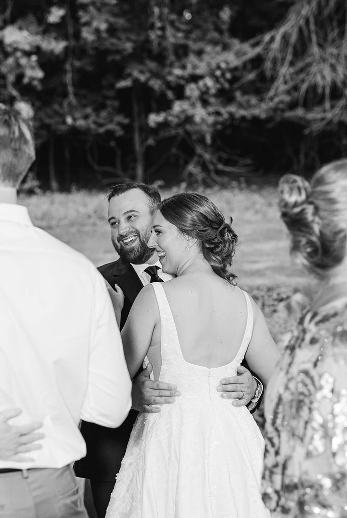 Black-and-white candid photograph of wedding guests sharing a joyful moment during Allison and Cole’s intimate Northern Michigan wedding.