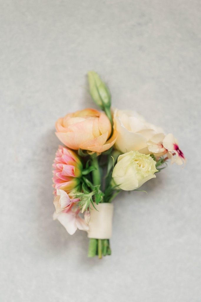 Peach, pink, and cream floral boutonniere designed by Leelanau Plant Company for Allison and Cole's Northern Michigan wedding.