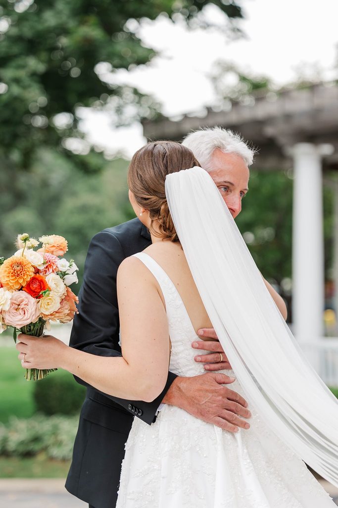 A sweet moment between Allison and her father as they embrace outside during her intimate Northern Michigan wedding at Black Star Farms.