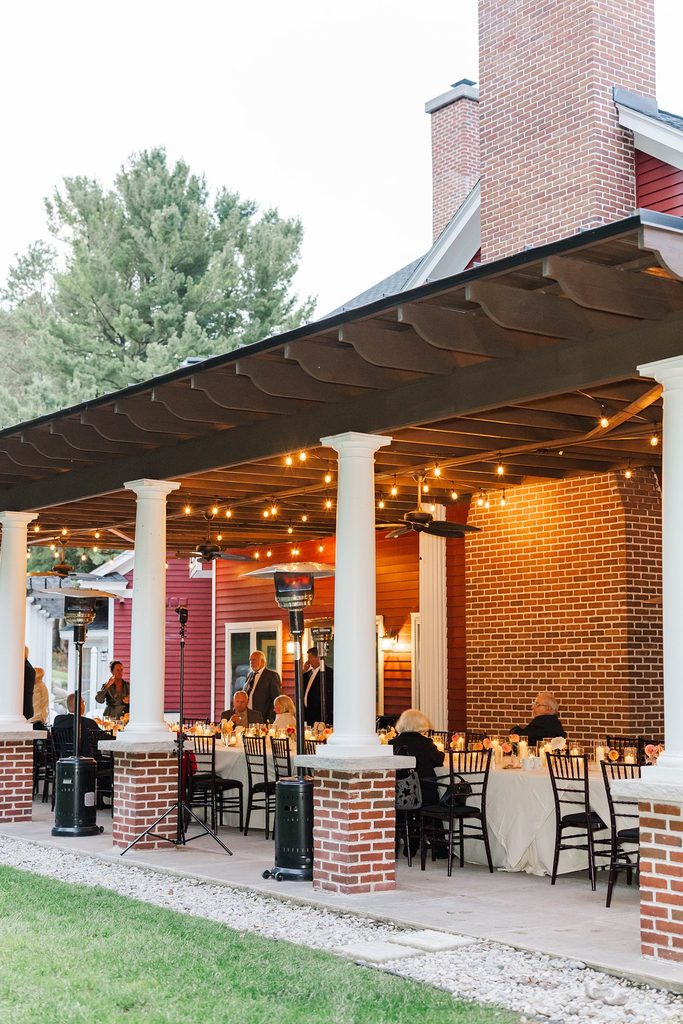 Guests enjoying an intimate wedding reception beneath the warmly lit covered patio at Black Star Farms in Suttons Bay, Michigan.