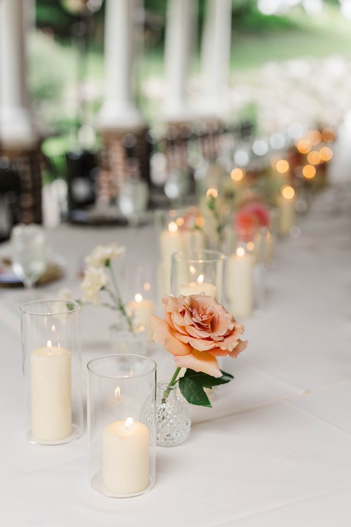 Peach rose and glowing candles decorating the intimate wedding reception table at Black Star Farms' Covered Patio in Northern Michigan.