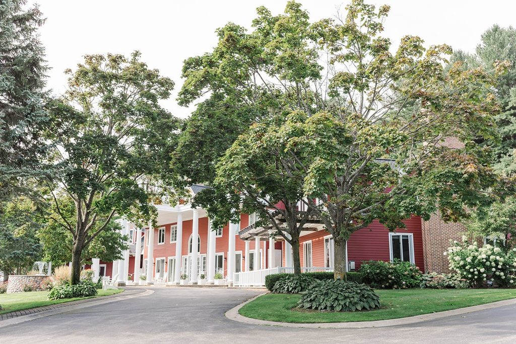 Exterior of the red Black Star Farms Inn with white columns and landscaped grounds, a Northern Michigan wedding venue in Suttons Bay.