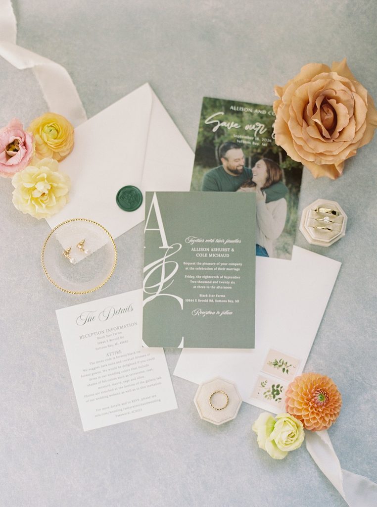 Allison and Cole's wedding invitation suite, gold rings, and colorful florals photographed on film for their Black Star Farms wedding in Suttons Bay.