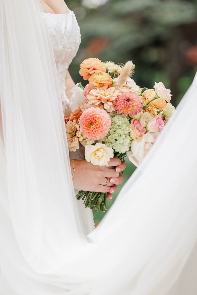 Colorful bridal bouquet featuring peach, pink, and yellow flowers designed by Leelanau Plant Company for a Black Star Farms wedding in Northern Michigan.