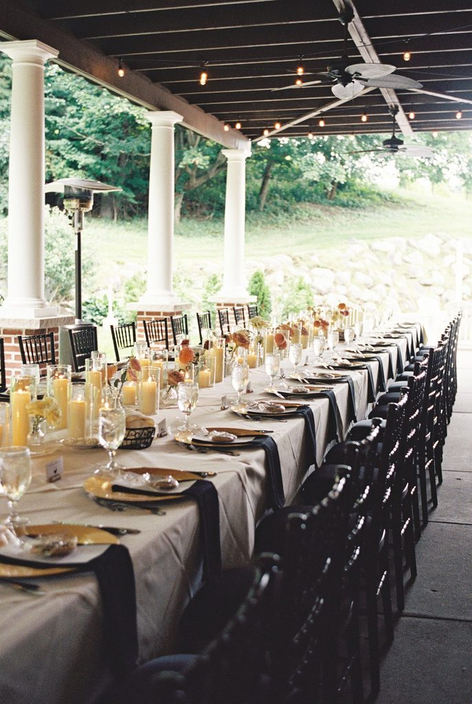 Elegant long-table wedding reception setup with floral centerpieces, candles, and place settings beneath the covered patio at Black Star Farms.