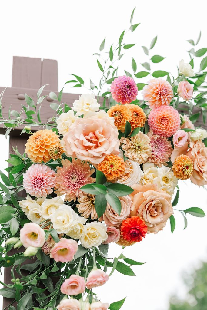 Close-up of colorful peach, orange, and pink wedding flowers designed by Leelanau Plant Company for the vineyard ceremony at Black Star Farms.