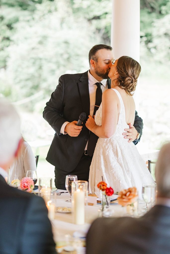 Allison and Cole share a kiss during their intimate wedding reception beneath the covered patio at Black Star Farms in Suttons Bay, Michigan.